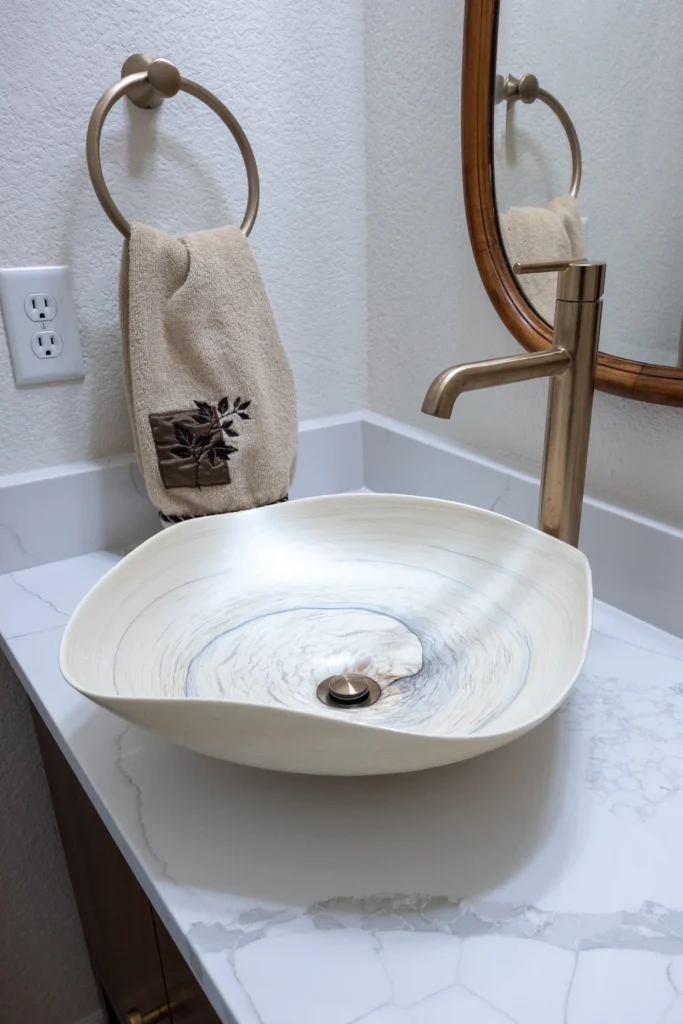 Powder room remodel in Broomfield, CO by Northbuilt Construction featuring a vessel sink, wood vanity, and vintage-style mirror for a warm, transitional look.